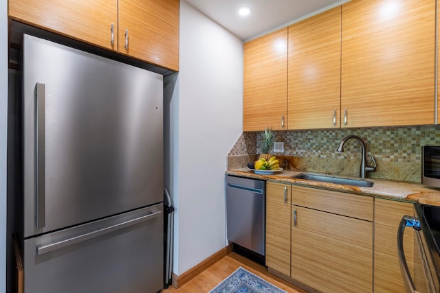 kitchen with sink, light hardwood / wood-style flooring, backsplash, appliances with stainless steel finishes, and stone countertops