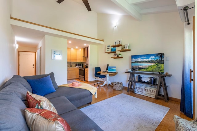 living room featuring ceiling fan, high vaulted ceiling, beamed ceiling, and light wood-type flooring