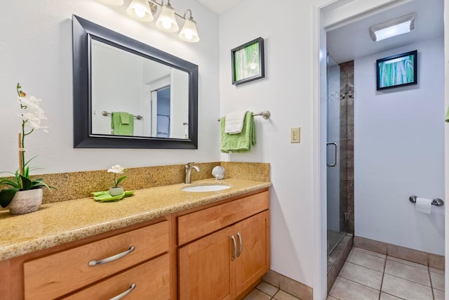 bathroom featuring tile patterned floors, baseboards, vanity, and a stall shower
