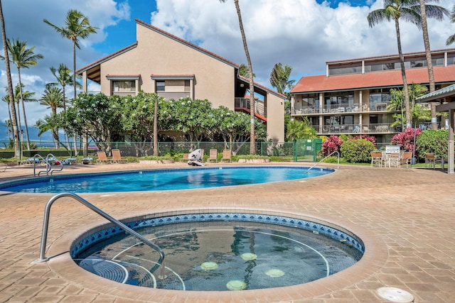 pool featuring a community hot tub, a patio, and fence