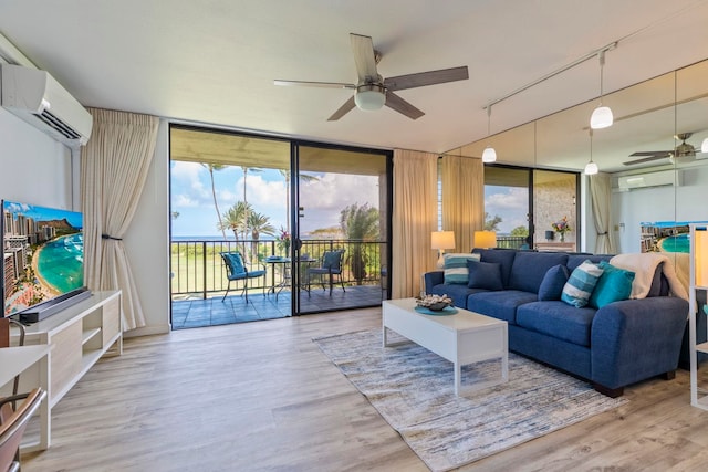 living room featuring ceiling fan, expansive windows, wood finished floors, and a wall unit AC