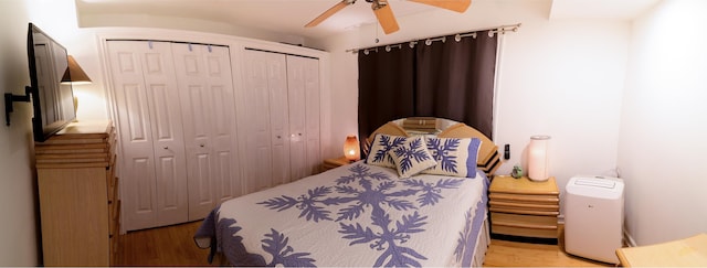 bedroom featuring ceiling fan, multiple closets, and light hardwood / wood-style flooring