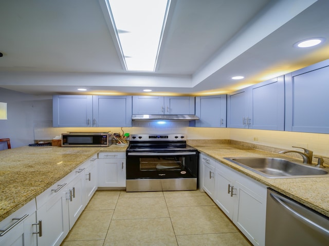 kitchen with appliances with stainless steel finishes, backsplash, sink, light tile patterned floors, and white cabinets