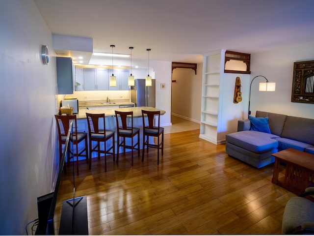 living room with built in shelves, hardwood / wood-style floors, and sink