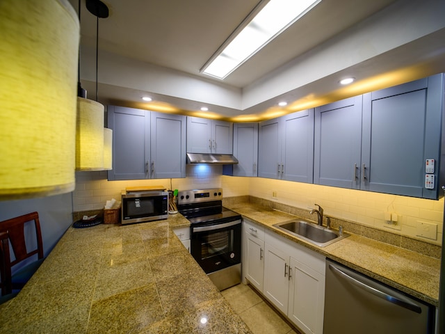 kitchen with decorative backsplash, sink, stainless steel appliances, and hanging light fixtures