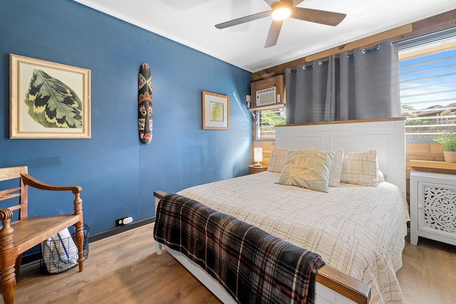 bedroom featuring ceiling fan, a wall unit AC, and light hardwood / wood-style floors