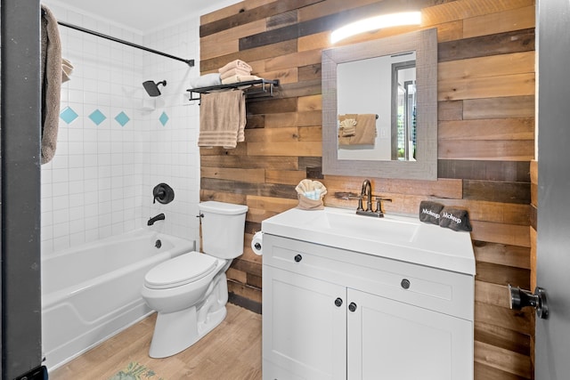 full bathroom with hardwood / wood-style floors, tiled shower / bath combo, wood walls, toilet, and vanity