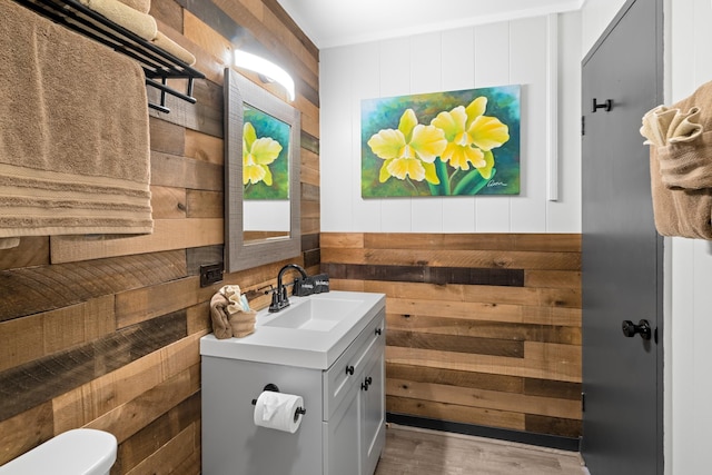 bathroom featuring wooden walls, vanity, hardwood / wood-style floors, and toilet