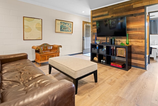 living room featuring wood walls, light hardwood / wood-style floors, and ornamental molding