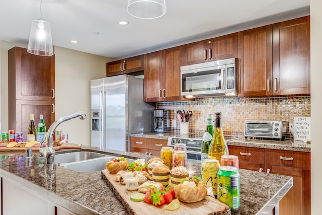 kitchen with appliances with stainless steel finishes, hanging light fixtures, backsplash, sink, and light stone countertops