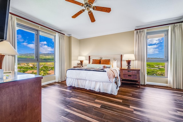 bedroom featuring ceiling fan, crown molding, dark wood-type flooring, and multiple windows