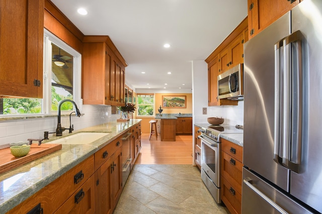 679 Kaapuni Pl, Kihei, HI 96753 - kitchen featuring appliances with stainless steel finishes, brown cabinetry, recessed lighting, decorative backsplash, and light stone counters