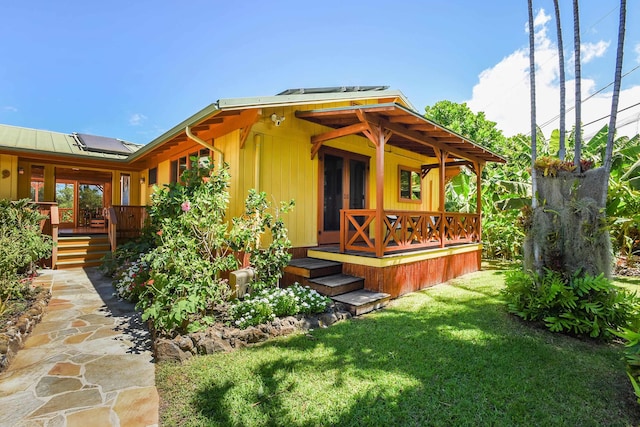 679 Kaapuni Pl, Kihei, HI 96753 - rear view of property featuring a porch, a yard, roof mounted solar panels, a standing seam roof, and a metal roof