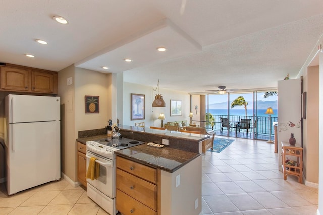 kitchen with ceiling fan, a wall of windows, kitchen peninsula, white appliances, and light tile patterned floors