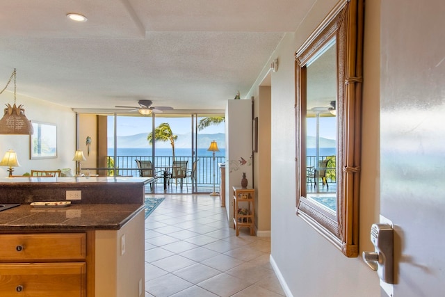 kitchen featuring a wealth of natural light, a water and mountain view, ceiling fan, and a wall of windows