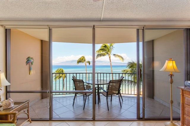 dining room with expansive windows, tile patterned flooring, a water view, and a textured ceiling