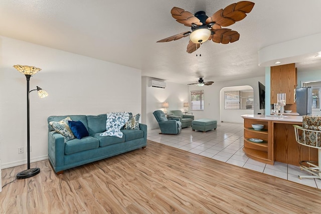 2730 Ohina St, Kihei, HI 96753 - living room featuring an AC wall unit, a ceiling fan, arched walkways, light tile patterned flooring, and baseboards