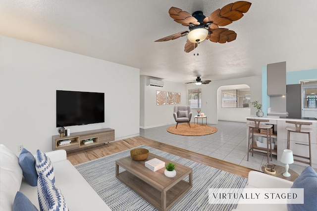 2730 Ohina St, Kihei, HI 96753 - living area with a wall mounted air conditioner, light wood-style floors, a ceiling fan, and plenty of natural light