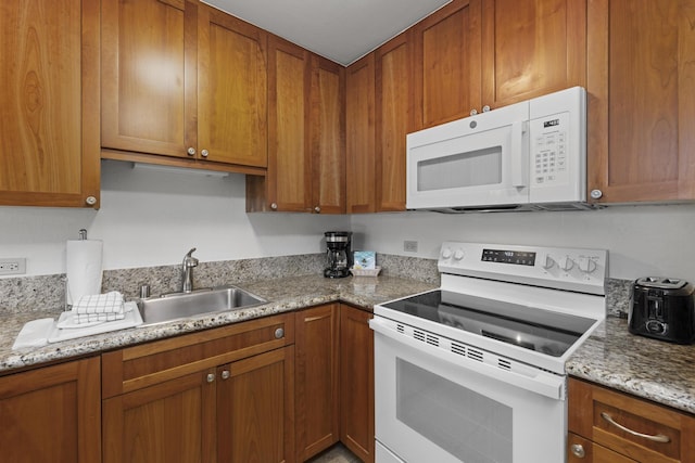 kitchen featuring light stone countertops, sink, and white appliances