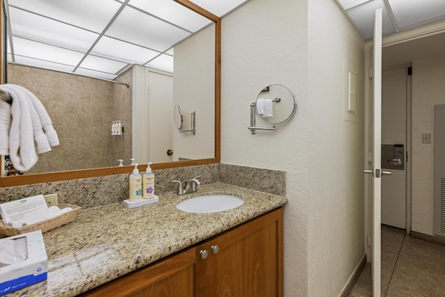 bathroom featuring vanity, a drop ceiling, and tile patterned floors