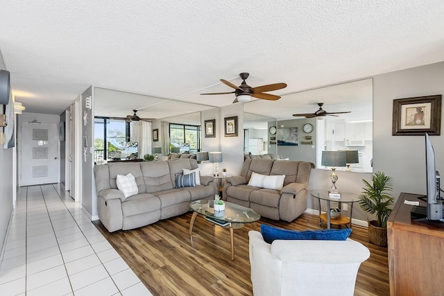 living area featuring a textured ceiling, light wood finished floors, and baseboards