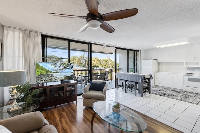 living room featuring a textured ceiling, ceiling fan, wood finished floors, and floor to ceiling windows