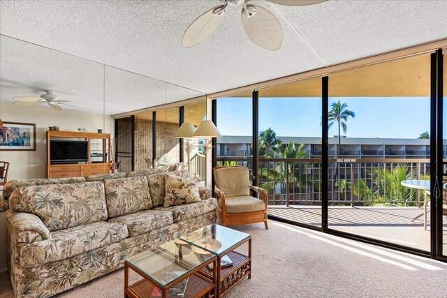 living room with ceiling fan, a wall of windows, carpet floors, and a textured ceiling
