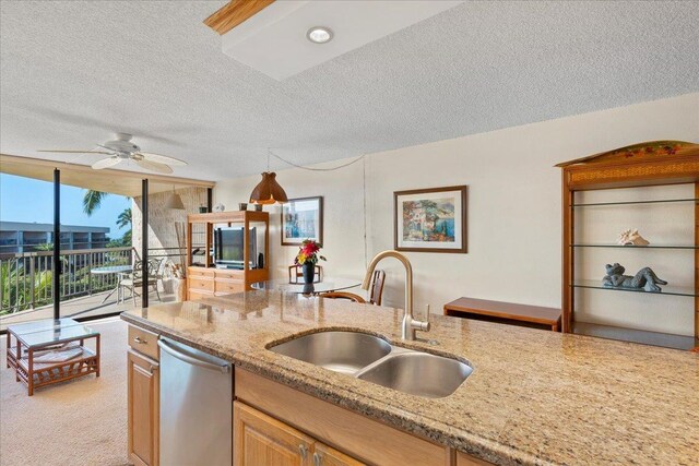 kitchen with a sink, dishwasher, a textured ceiling, light stone counters, and a ceiling fan