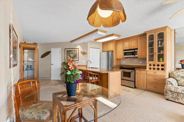 kitchen featuring stainless steel appliances, glass insert cabinets, light stone countertops, a textured ceiling, and a sink
