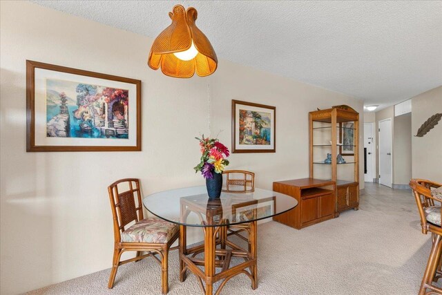 dining space with a textured ceiling and light colored carpet
