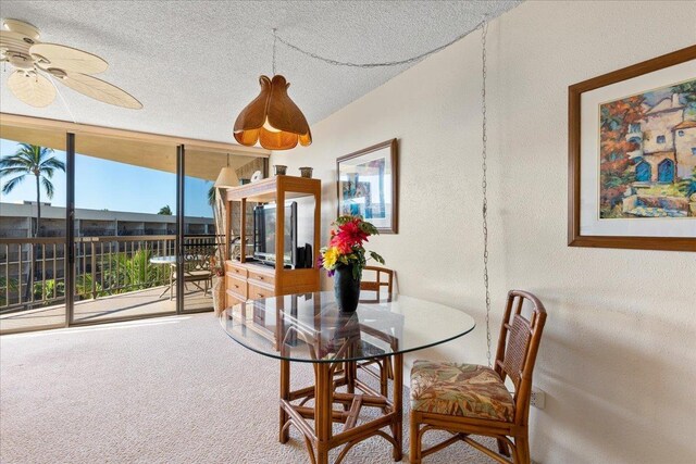 carpeted dining space with a textured ceiling, a textured wall, and ceiling fan