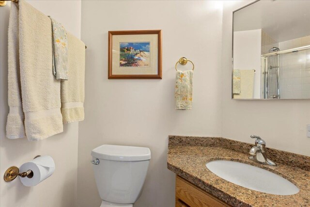 bathroom featuring a shower stall, toilet, and vanity