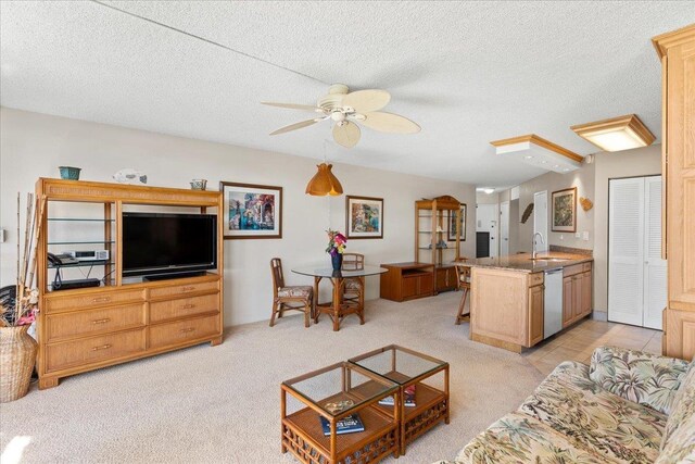 living room featuring ceiling fan, a textured ceiling, and light carpet