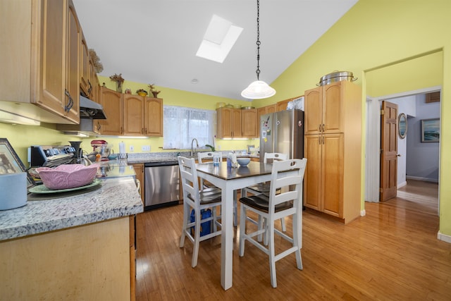 kitchen with a skylight, light hardwood / wood-style flooring, appliances with stainless steel finishes, pendant lighting, and light stone countertops