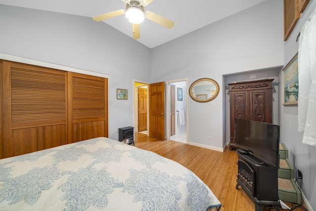 bedroom with ceiling fan, high vaulted ceiling, a closet, and light wood-type flooring