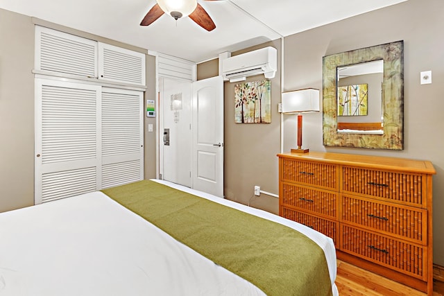 bedroom featuring a wall unit AC, ceiling fan, a closet, and light wood-type flooring