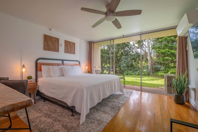 bedroom with wood-type flooring, floor to ceiling windows, access to outside, and ceiling fan