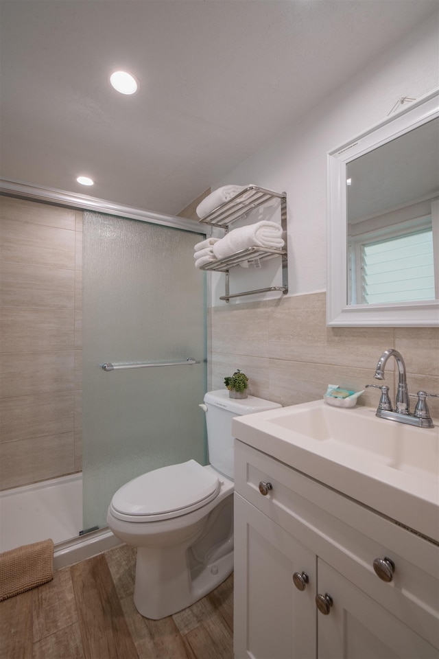 bathroom featuring toilet, an enclosed shower, wood-type flooring, tile walls, and vanity