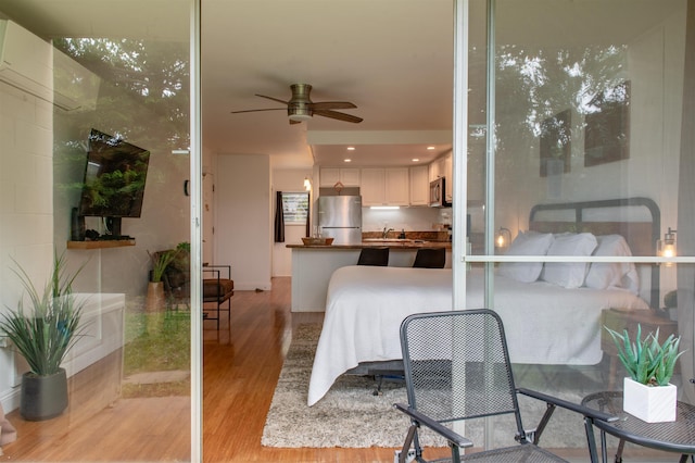 bedroom with sink, stainless steel refrigerator, and light hardwood / wood-style flooring