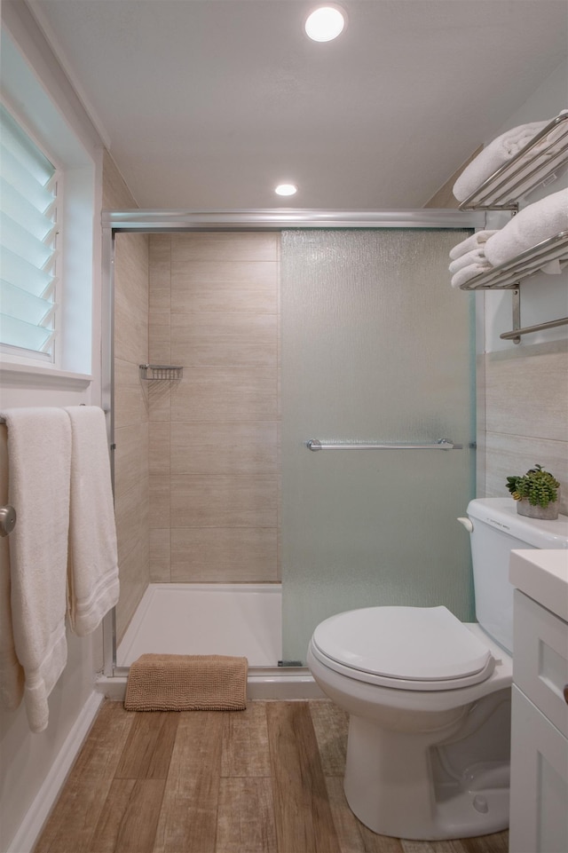 bathroom with hardwood / wood-style flooring, vanity, toilet, and a shower with door