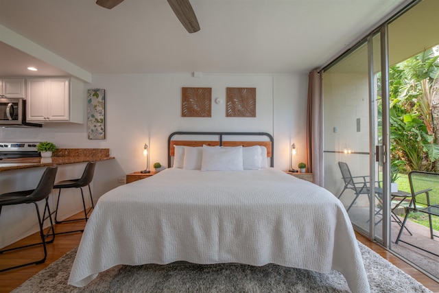 bedroom featuring ceiling fan, a wall of windows, light hardwood / wood-style floors, and multiple windows