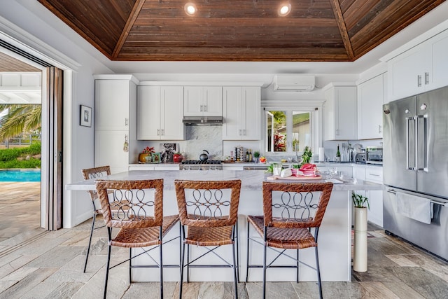 kitchen featuring wooden ceiling, a breakfast bar, appliances with stainless steel finishes, white cabinetry, and a center island