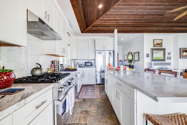 kitchen with premium appliances, a kitchen bar, tasteful backsplash, white cabinets, and dark tile floors