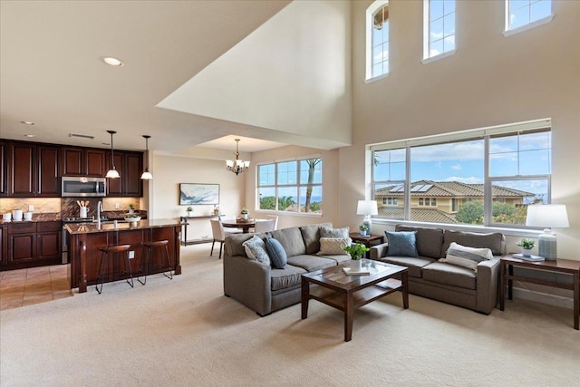 living room featuring light carpet, a towering ceiling, and a chandelier