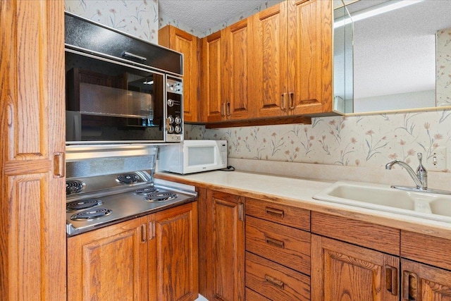 kitchen featuring stovetop, a textured ceiling, and sink