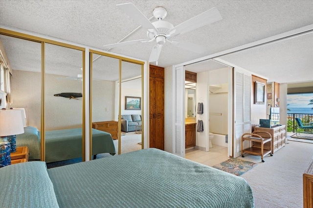 carpeted bedroom featuring multiple closets, ceiling fan, ensuite bathroom, and access to exterior