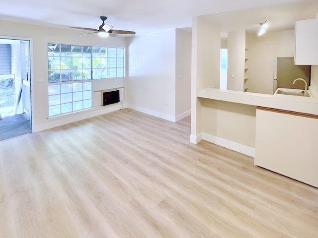 unfurnished living room with ceiling fan, sink, and light hardwood / wood-style flooring