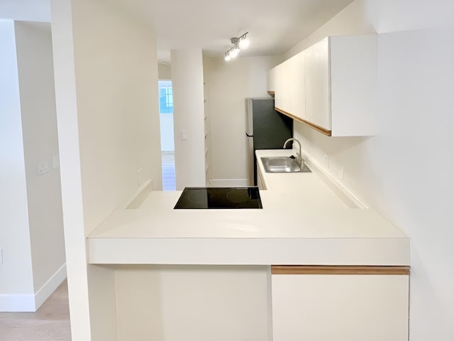 kitchen with black electric cooktop, white cabinetry, and sink