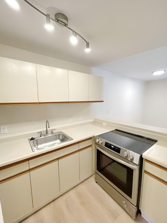 kitchen featuring light hardwood / wood-style floors, stainless steel electric range oven, sink, and cream cabinets