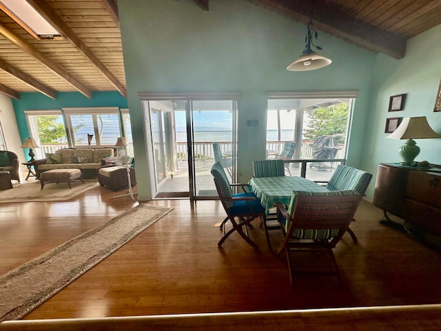 dining space featuring vaulted ceiling with skylight, a water view, a wealth of natural light, and hardwood / wood-style floors